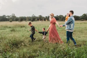 Family walking in a grassy field at sunset.