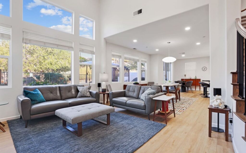 A living room with two sofas, an ottoman, and a dining area.