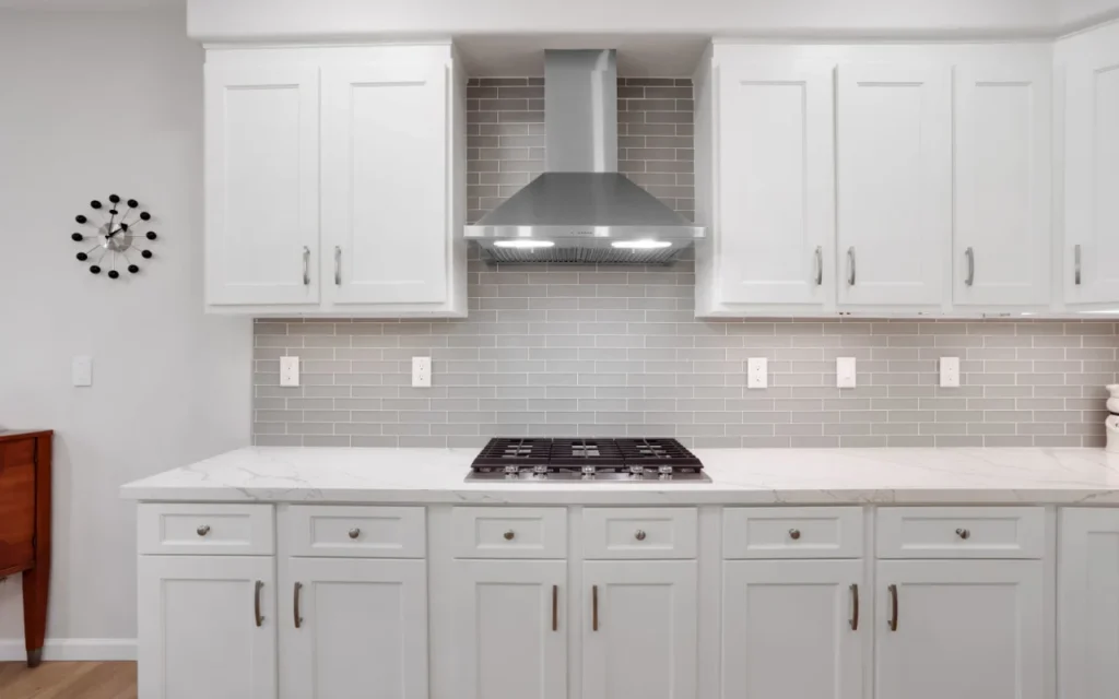 A modern kitchen with white cabinets and stainless steel appliances.
