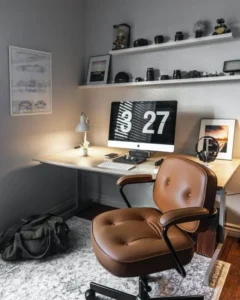 A desk with a computer, chair, and shelves on the wall.