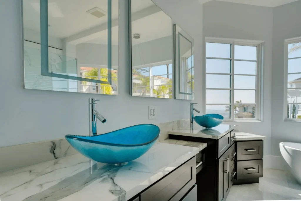 Two blue glass vessel sinks on marble vanity.
