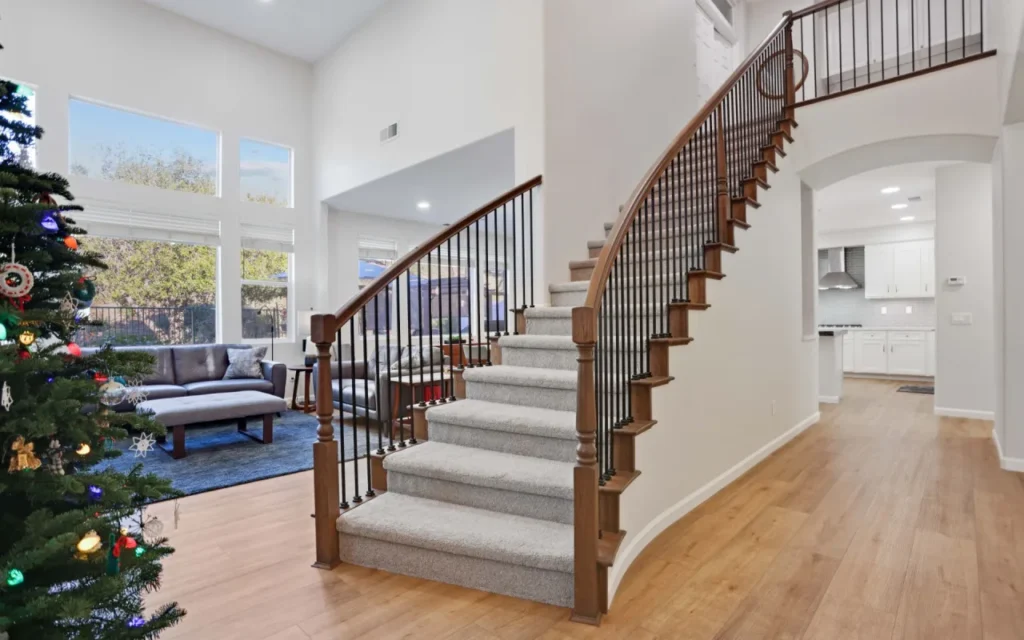 A curved staircase with wood handrails and carpeted steps.