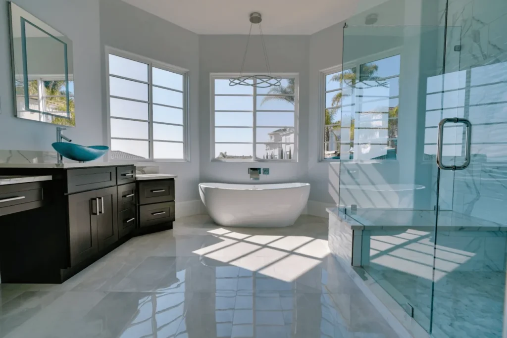 Modern bathroom with large windows and white bathtub.