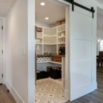White barn door leads to a well organized pantry.