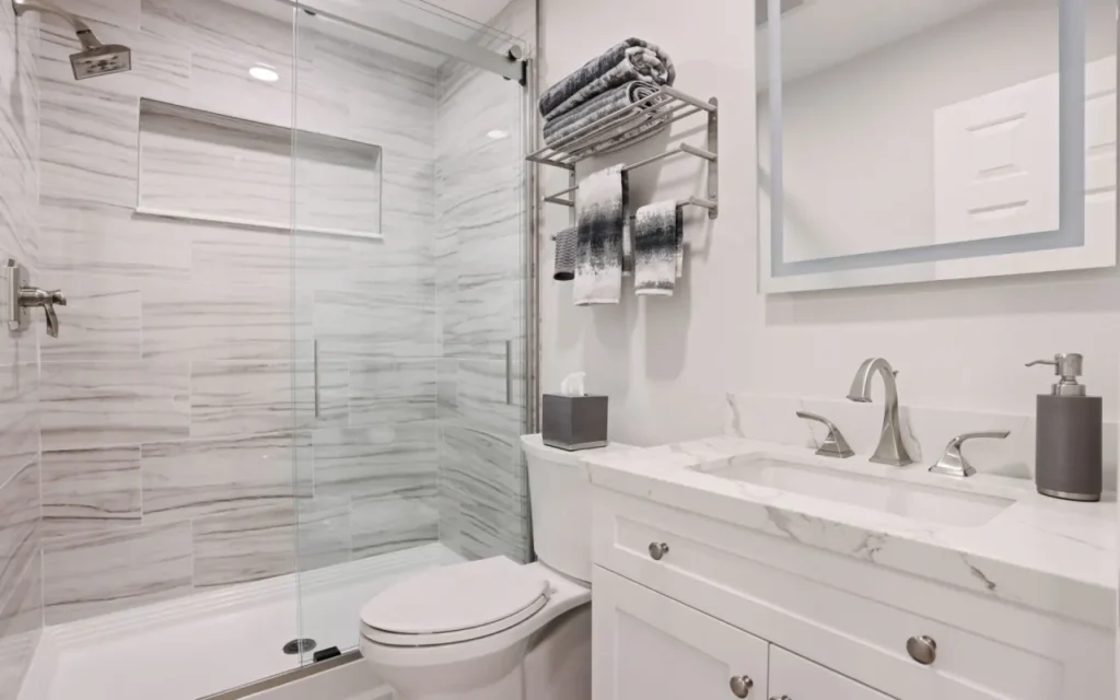 White and grey bathroom with toilet, sink and shower.