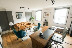 Office with brown leather sofa and blue armchairs.