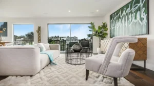 Bright living room with white furniture and green plants.