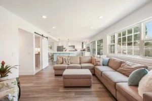 A living room with a large couch, coffee table, and kitchen in the background.