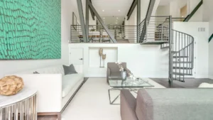 A living room with a spiral staircase and a green wall.