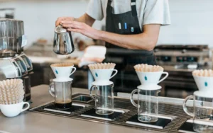 Barista pouring hot water into coffee filters.