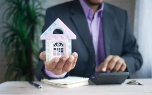 A person holding a model house in their hand.