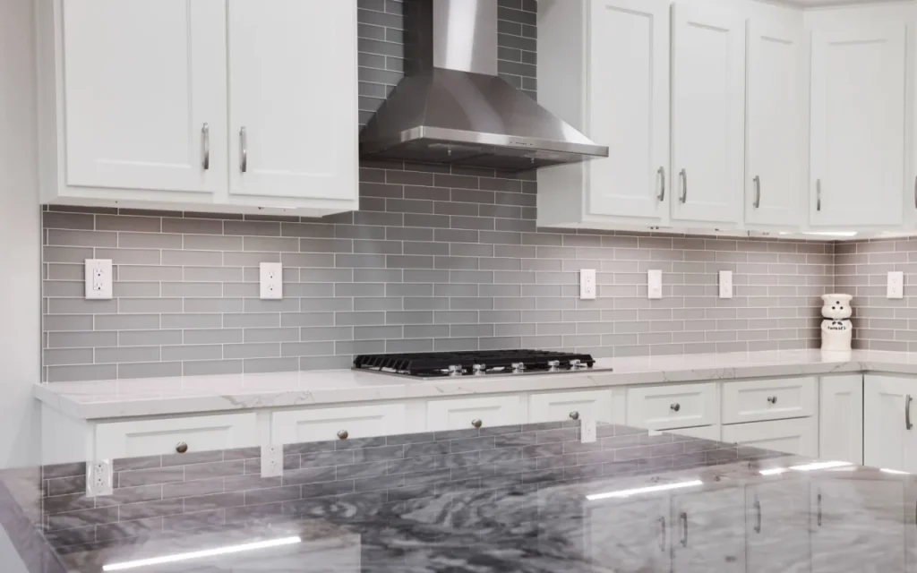 Modern kitchen with white cabinets and gray tile backsplash.