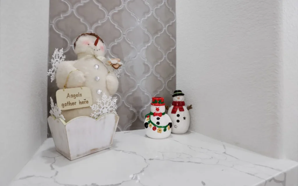 Three snowmen figurines on a marble table.