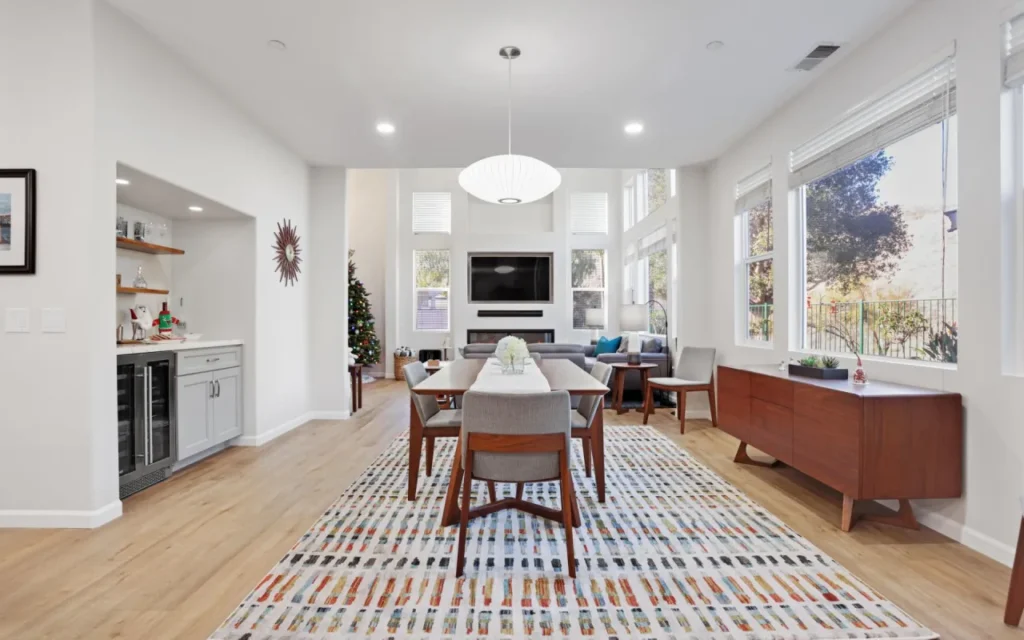 A dining room with a table, chairs, and a rug.