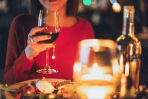 A woman is holding a glass of red wine.