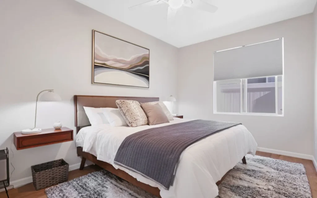 A bedroom with a bed, nightstand, lamp, and window.