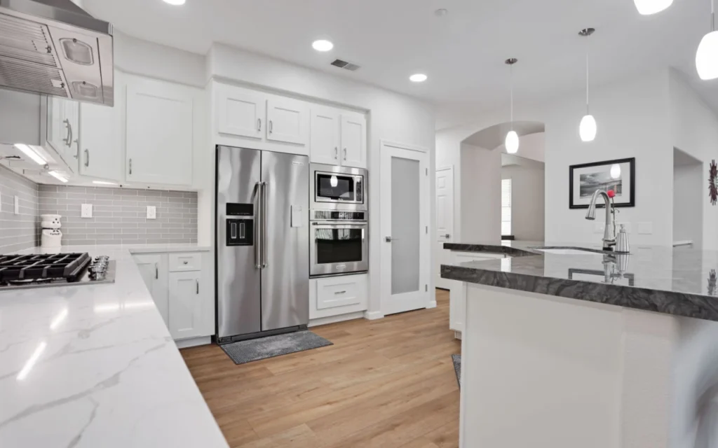 White kitchen with stainless steel appliances and large island.