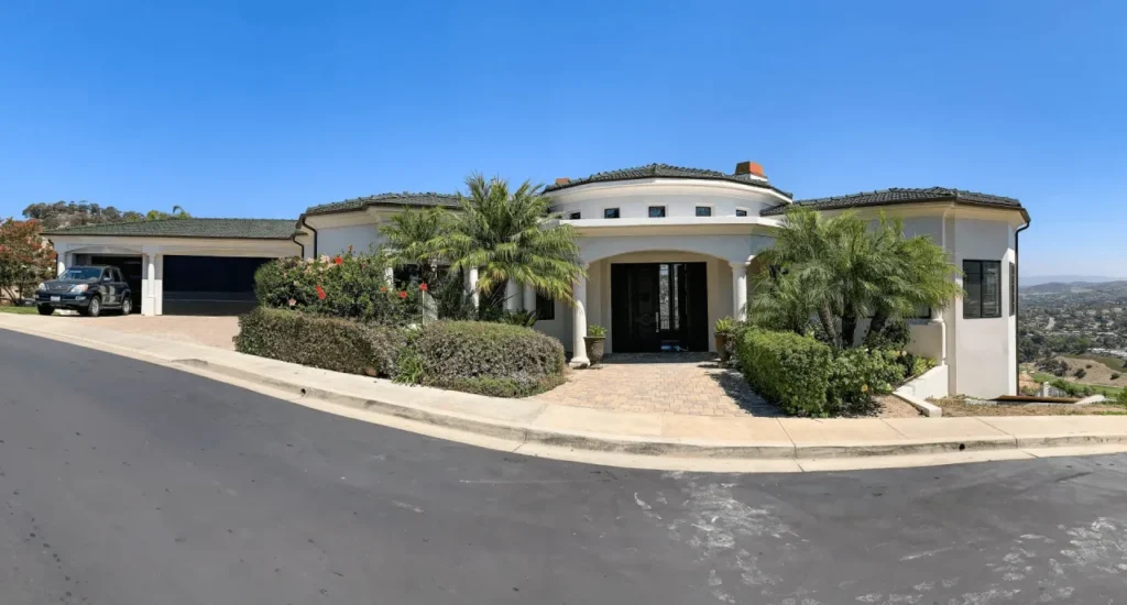 Large white house with palm trees in front.