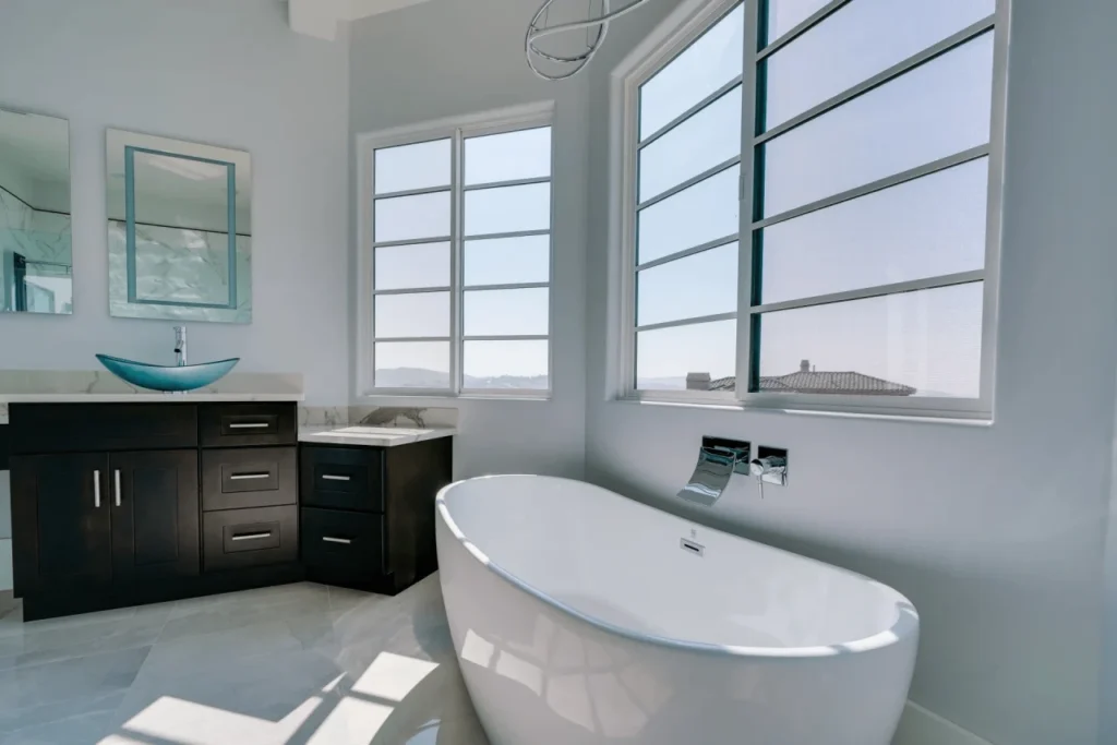 Modern bathroom with large bathtub and windows.