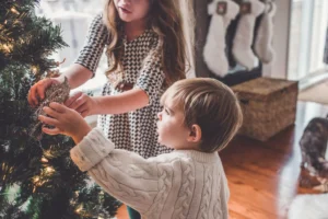 Two children hanging ornaments on a Christmas tree.