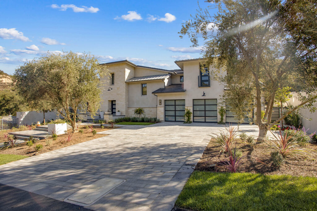 Modern house exterior with large driveway and trees.