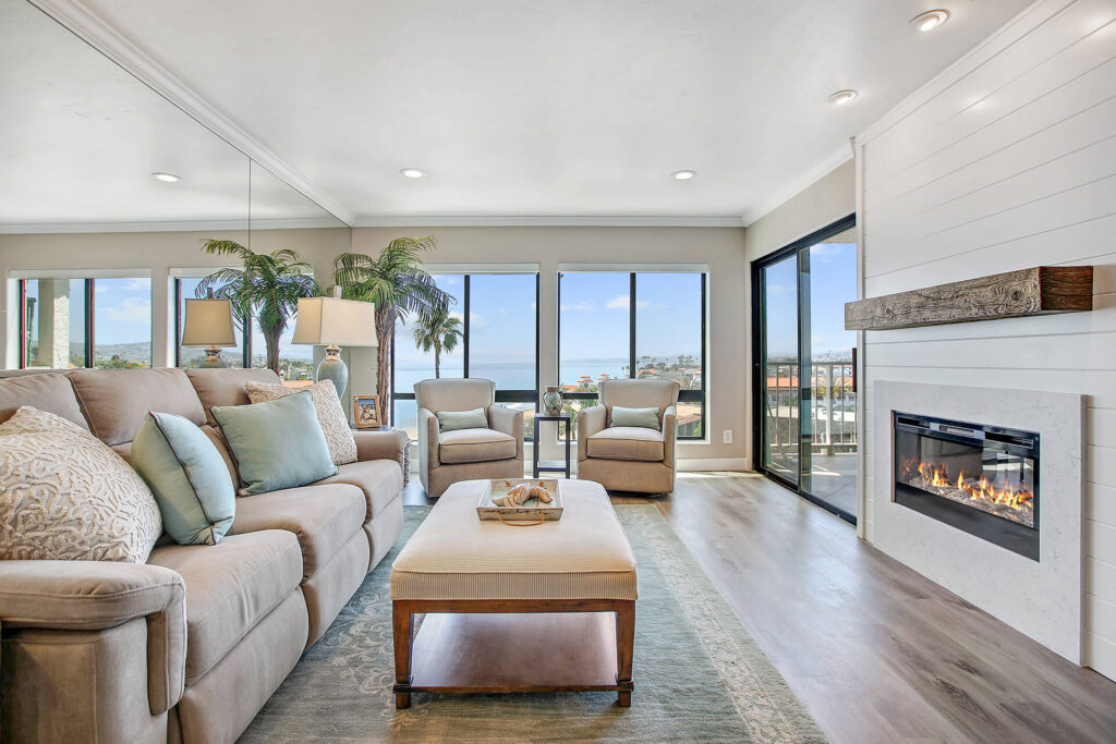 Living room with fireplace, sofa, armchairs, and ocean view.