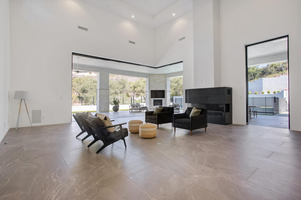 Modern living room with high ceiling and large glass windows.
