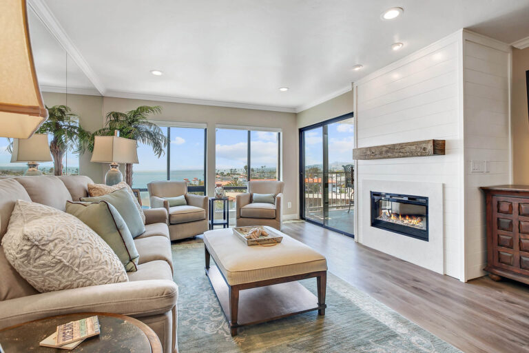 Living room with fireplace, TV, and ocean view.