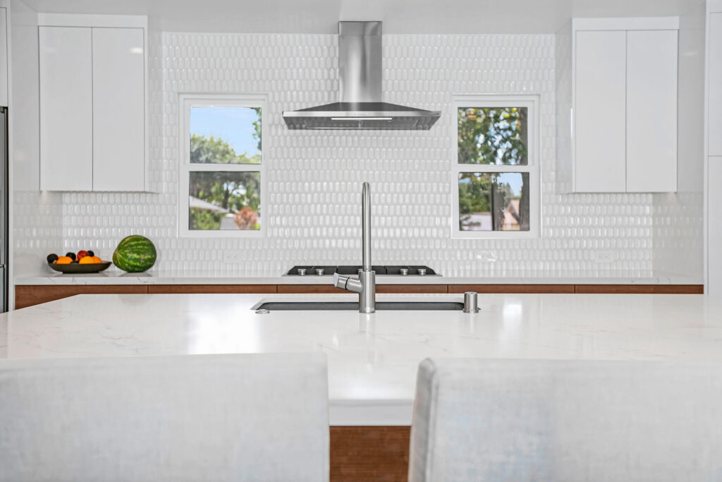 Modern kitchen with white cabinets and stainless steel appliances.