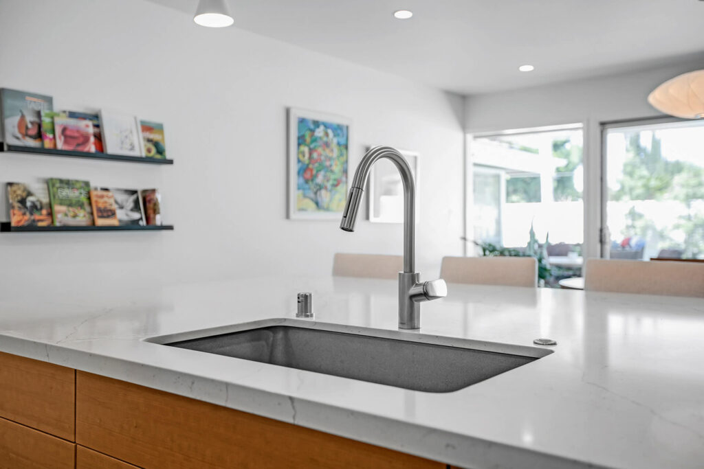 A kitchen sink and faucet with a view of the backyard.