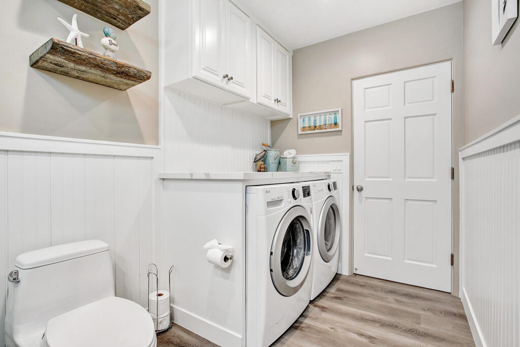 A toilet and washing machine in a laundry room.