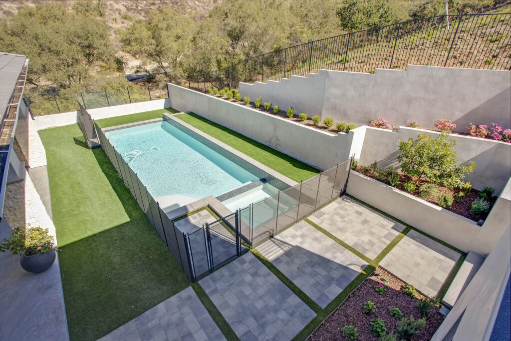 Backyard with pool, artificial grass, and garden.