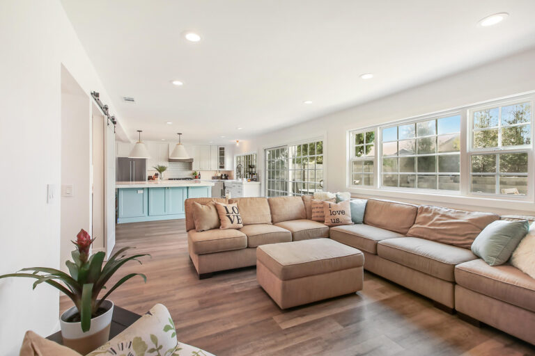 A living room with a large couch, coffee table, and kitchen in the background.