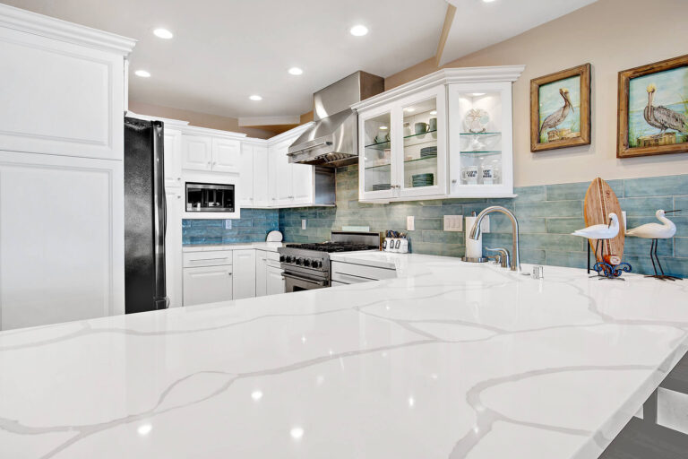 White kitchen with stainless steel appliances and quartz countertops.