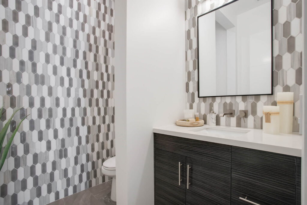 Bathroom with gray and white tile and dark vanity.