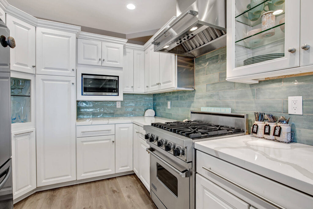 White kitchen with stainless steel appliances and blue tile backsplash.