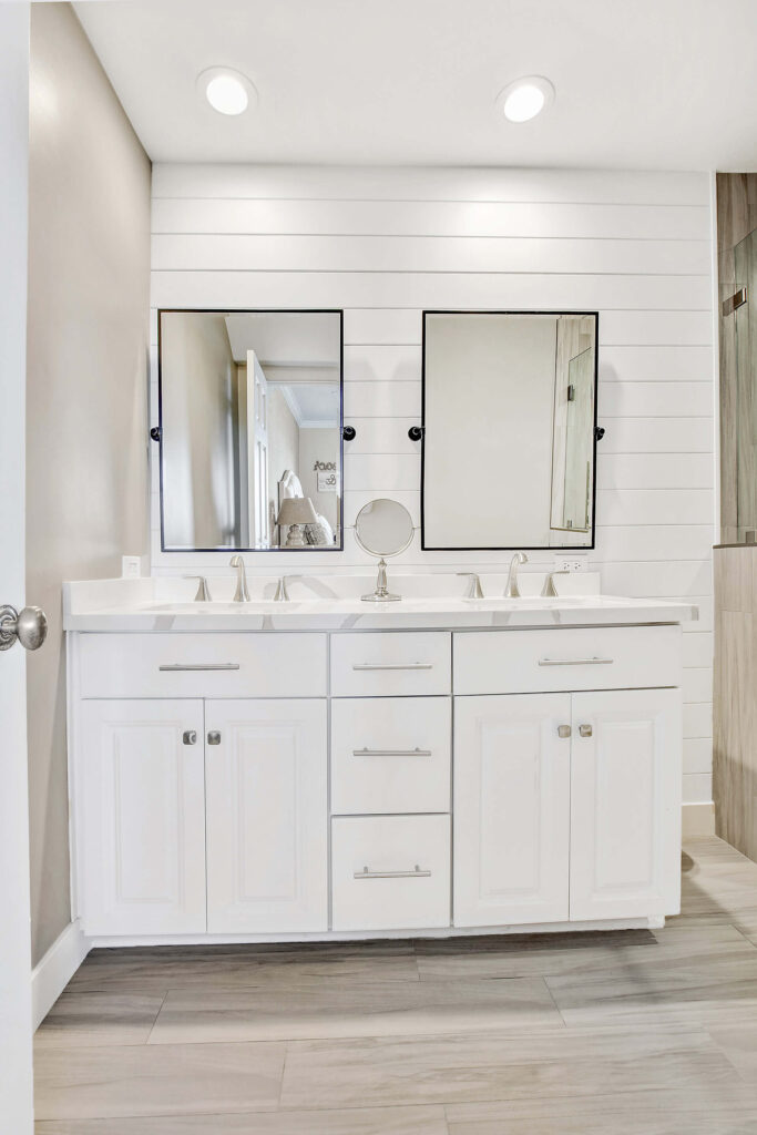 Double vanity with mirrors and shiplap wall.