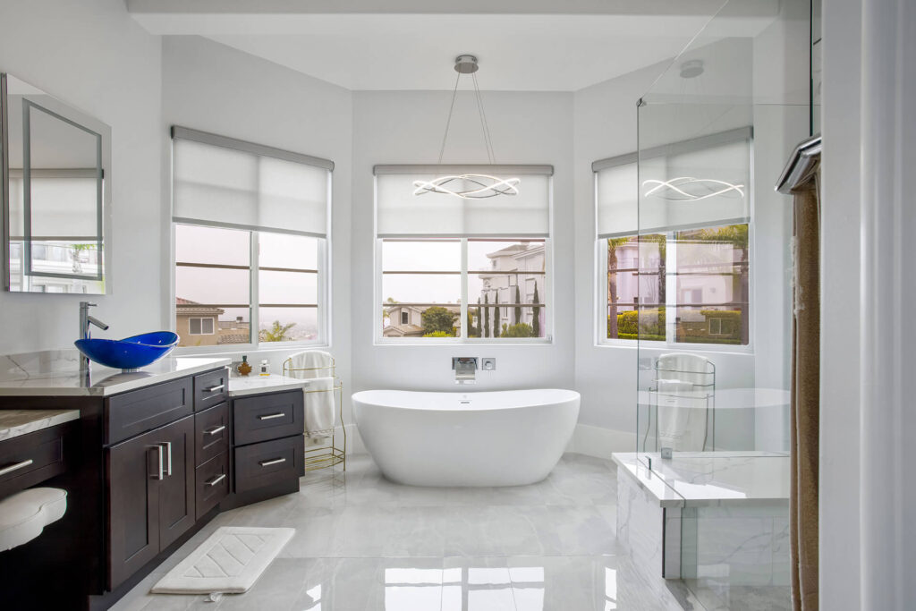 Modern bathroom with large windows and white bathtub.