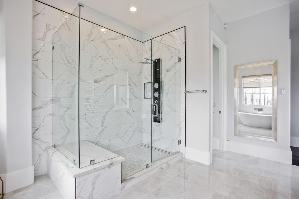 Modern bathroom with marble tiles and glass shower.