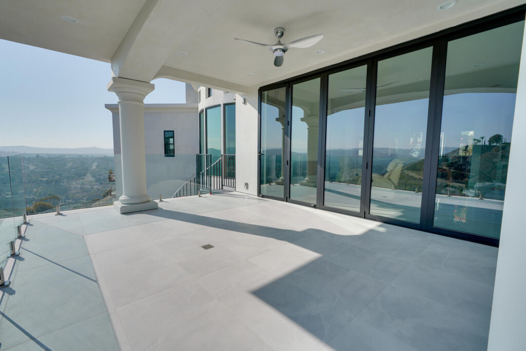 Balcony with glass railing and view of city.