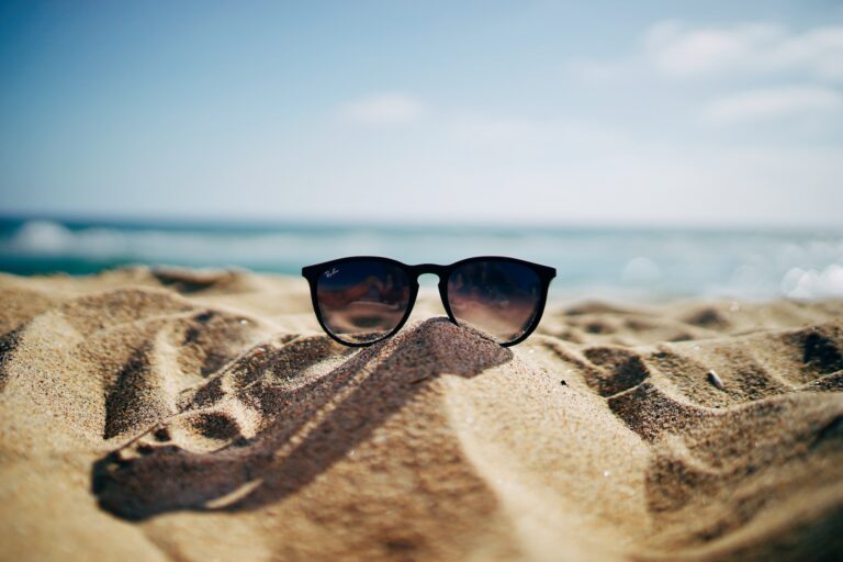 A pair of sunglasses sitting on top of the sand.
