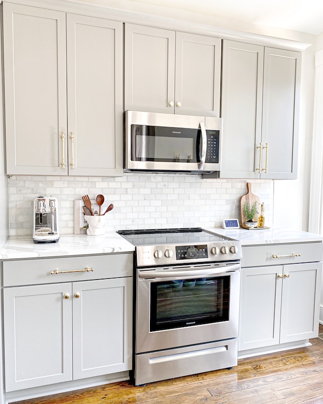 A kitchen with gray cabinets and stainless steel appliances.